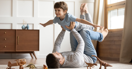 Pojke som ligger på sin pappas knän och flyger
