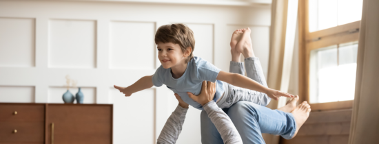 Pojke som ligger på sin pappas knän och flyger