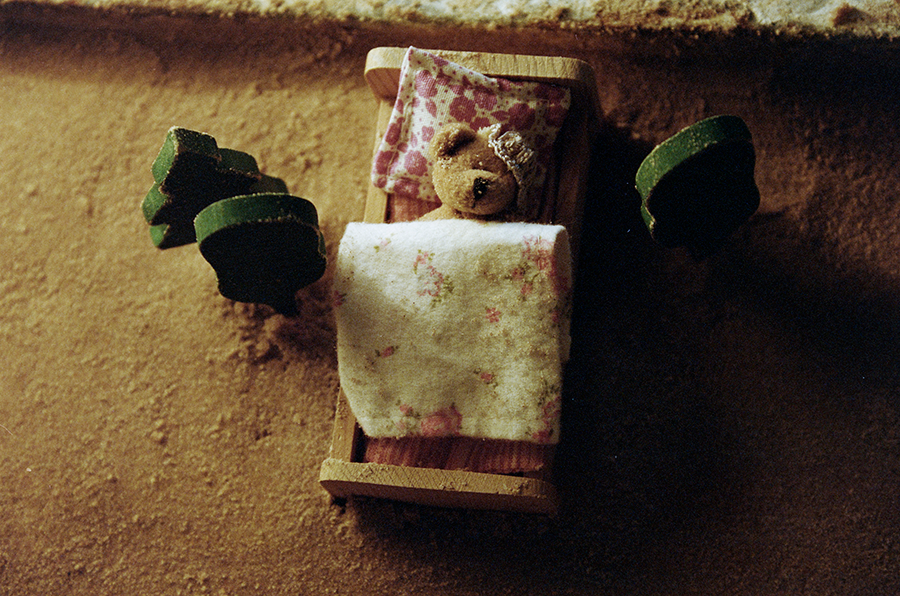 Nalle med bandage som ligger nedbäddad i en docksäng