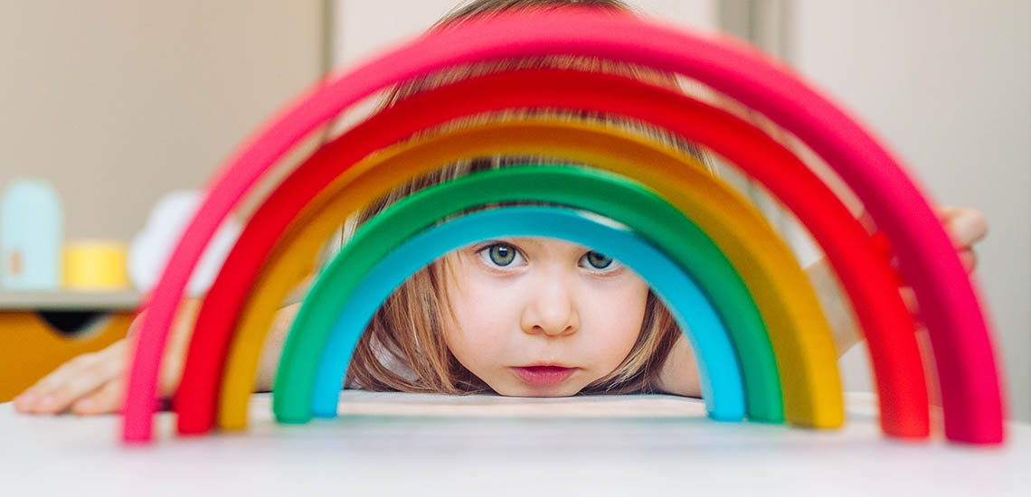 Flicka som tittar genom en leksaksregnbåge