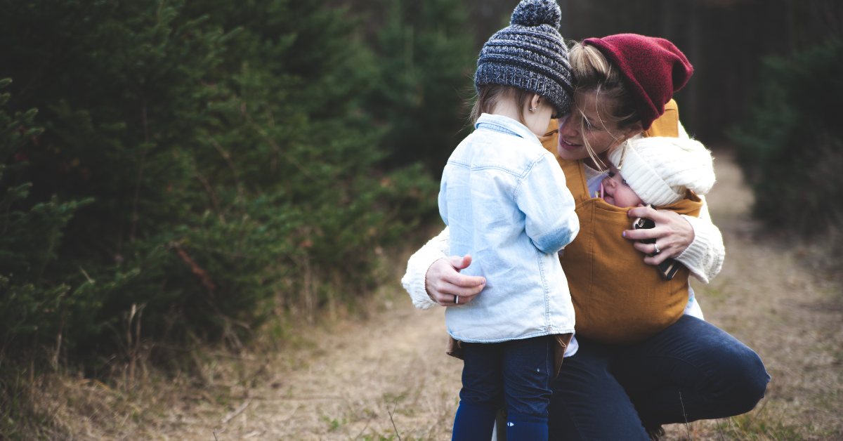 Bild på mamma med bebis som kramar ett småbarn