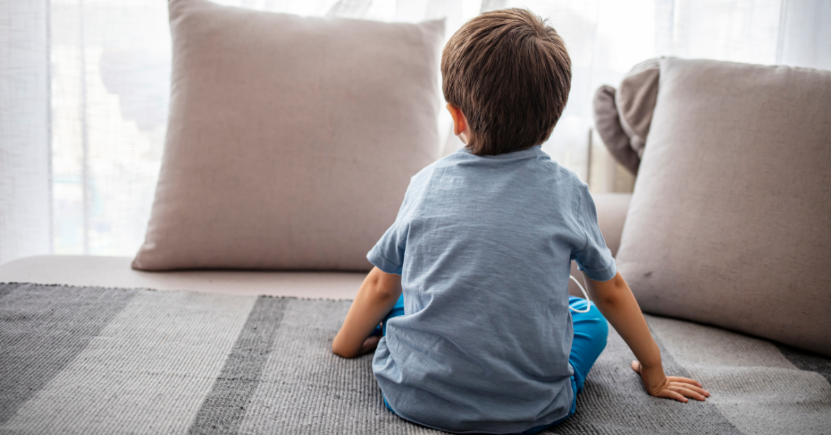 Bild på liten pojke som sitter på en säng.