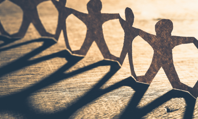 Pappersfigurer som håller varandra i handen