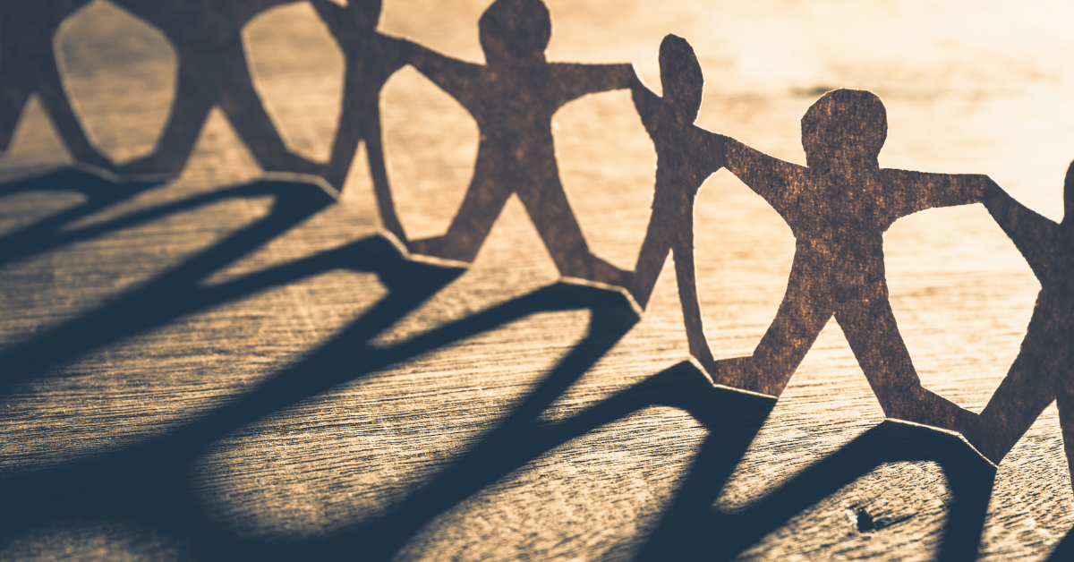 Pappersfigurer som håller varandra i handen