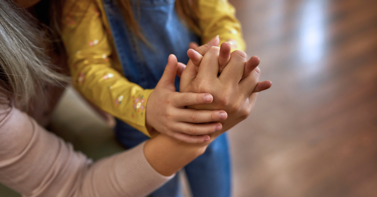 Bild på barn och vuxen som håller varandra i händerna.