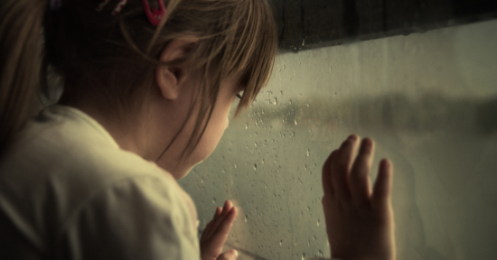 Flicka som tittar ut genom fönster